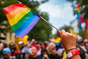 Photo of someone waving a rainbow pride flag in a parade. This photo represents how important support for the lgbtq community in Gallatin, TN is. 
