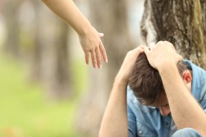A hand reaches out in support to a teen sitting against a tree. Learn more about how a teenage therapist in Gallatin, TN can offer support with counseling for teens in Gallatin, TN today. We offer a variety of services including teenage counseling and more.
