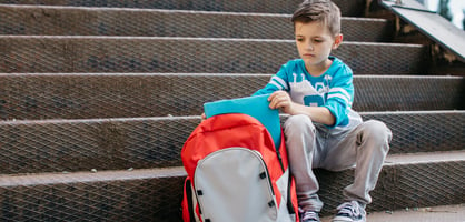 sad boy sitting on stairs, packing up his things 