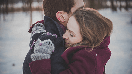 two-people-hugging-tightly-in-winter-snow-background